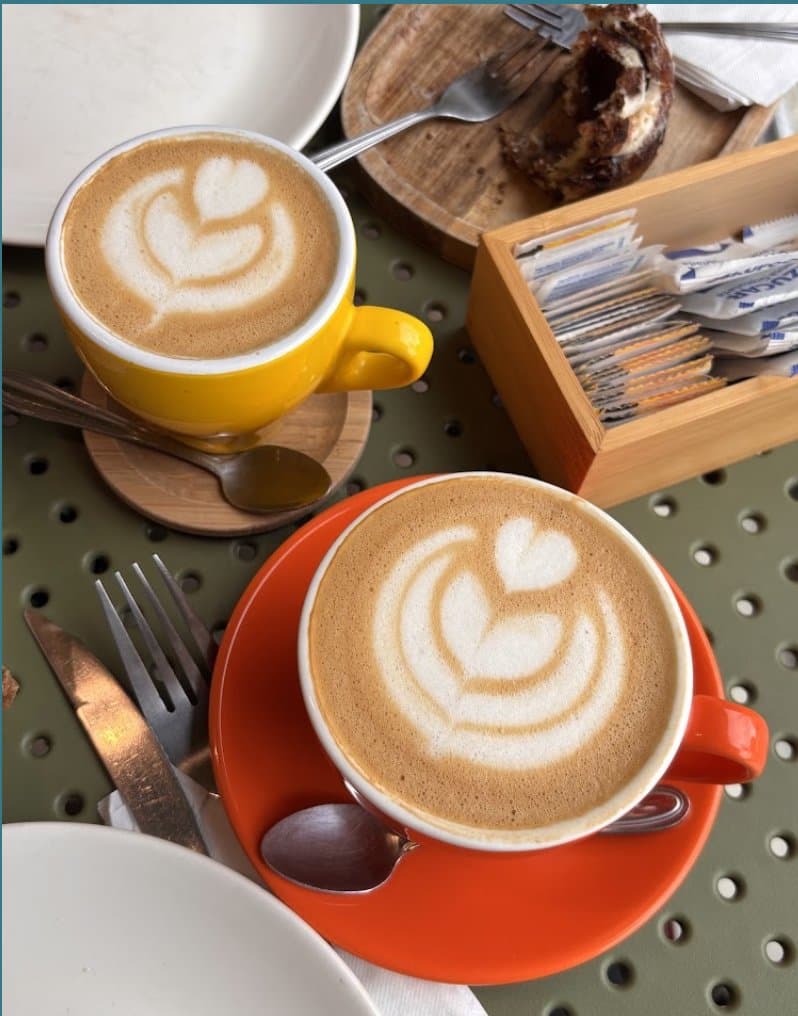 Dos capuchinos con arte latte en tazas de colores